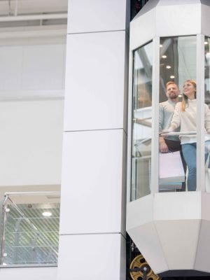 young-couple-with-paperbags-standing-elevator-while-moving-upwards-inside-large-contemporary-mall-shopping_1_11zon